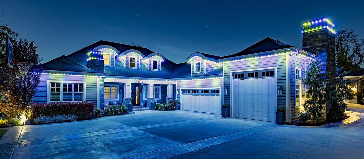 Wide home with blue and white lights across the roofline